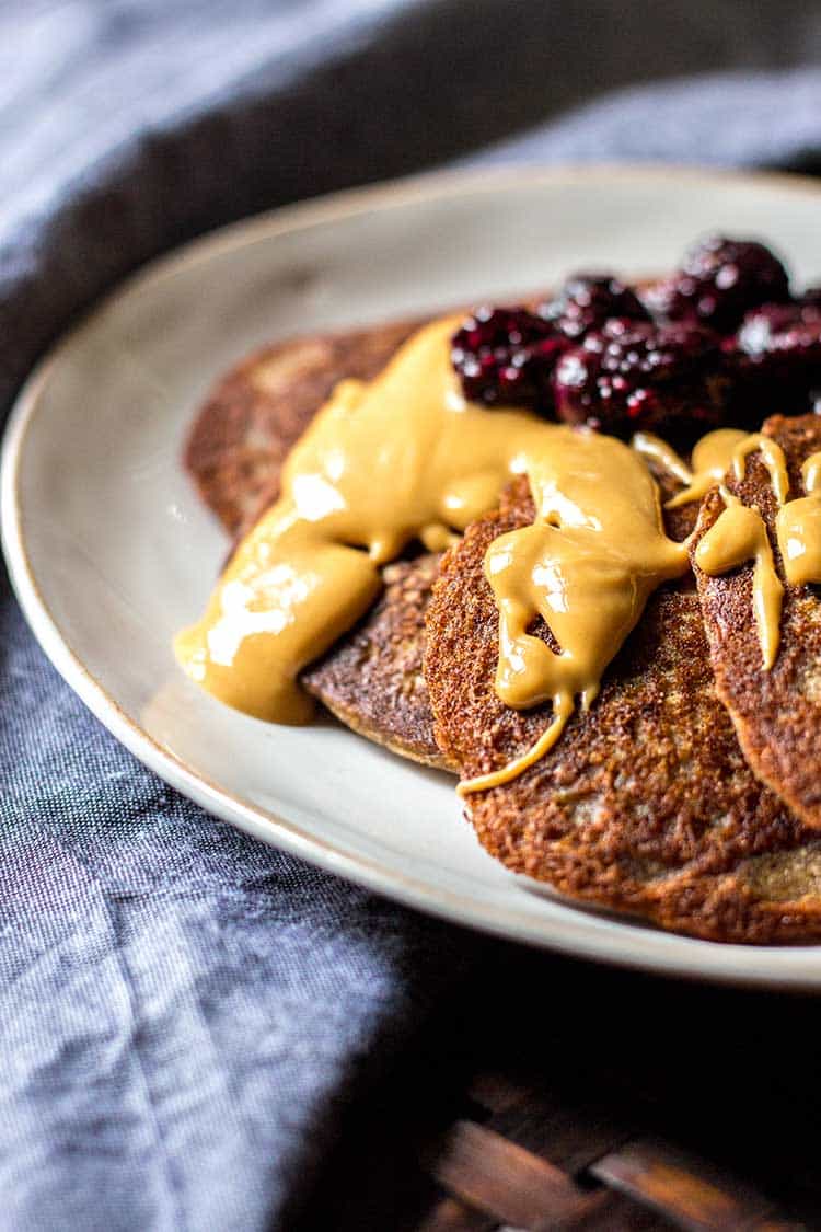 Picture of buckwheat pikelets, drizzled with runny peanut butter and a spoonful of blueberry chia jam (vegan and gluten free). 