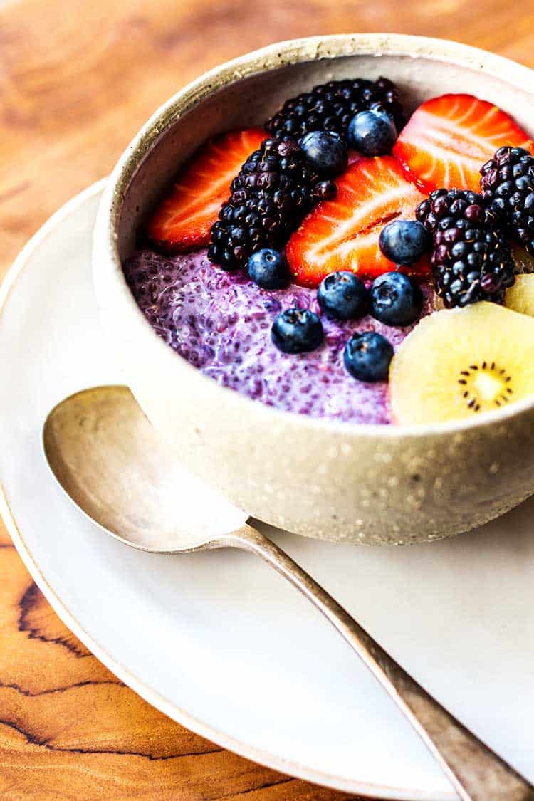 Blackcurrant and chia seed overnight oats with fresh berries and golden kiwifruit (vegan and gluten free). 