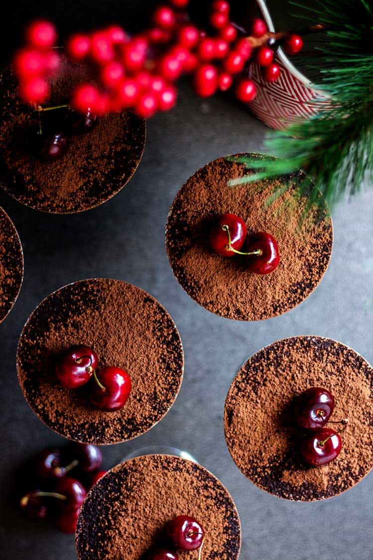 Overhead shot of vegan tiramisu served in martini glasses, dusted with cocoa. 