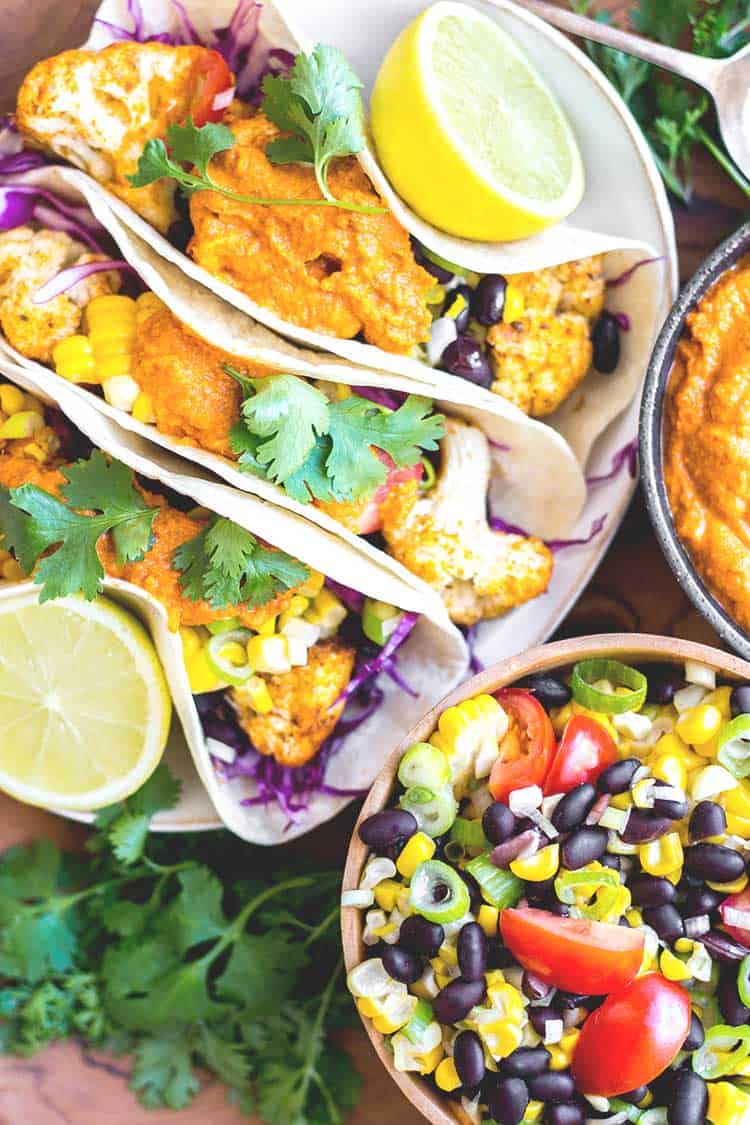 Overhead view of cauliflower tacos ready to serve, with almond chipotle salsa and salad (vegan and gluten free). 