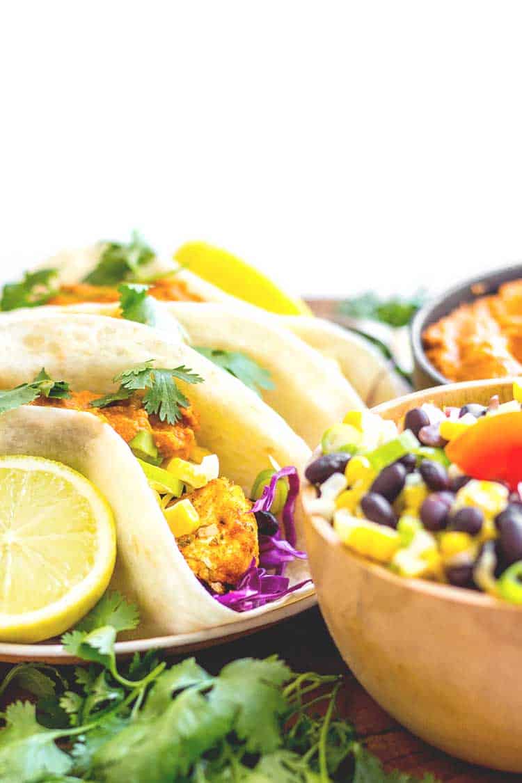 Side view of cauliflower tacos ready to serve, with almond chipotle salsa and salad (vegan and gluten free). 