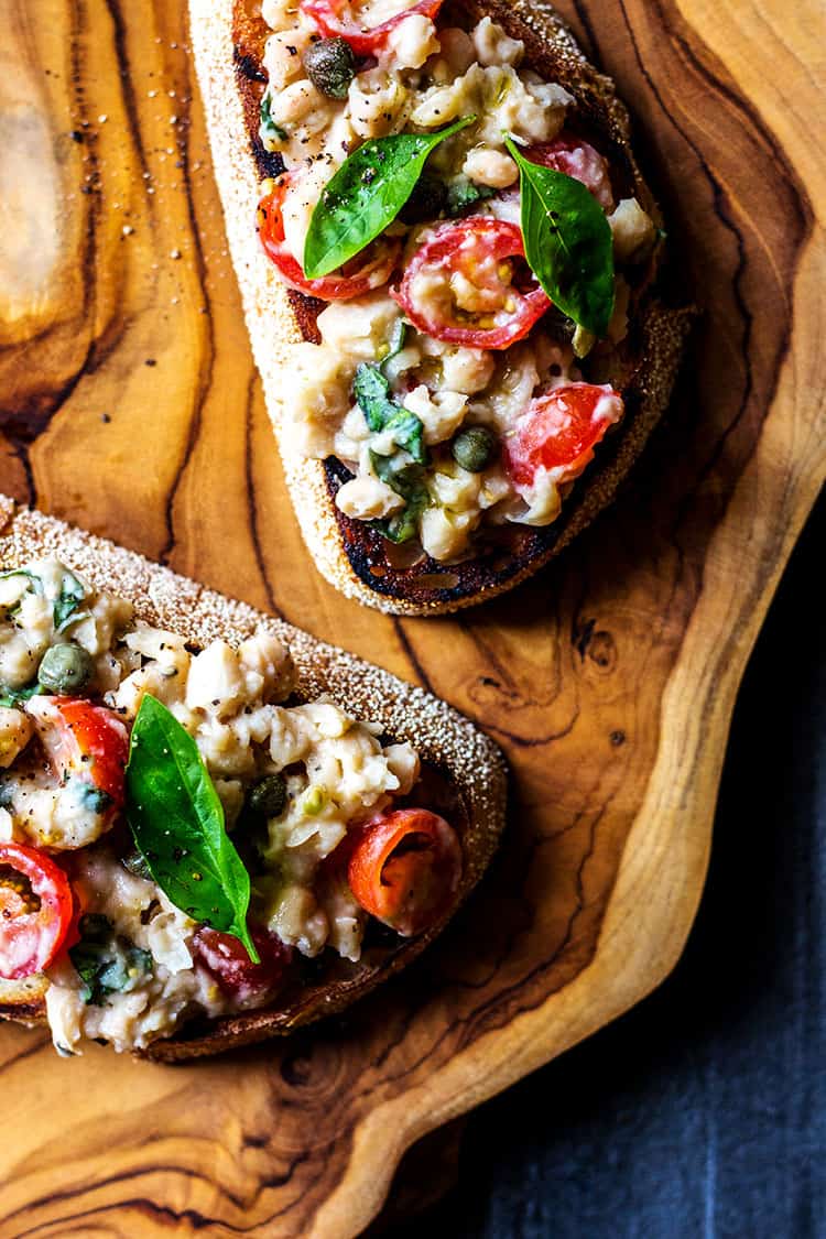 Overhead picture of two pieces of sourdough bruschetta, topped with cannellini bean and cherry tomato topping. 