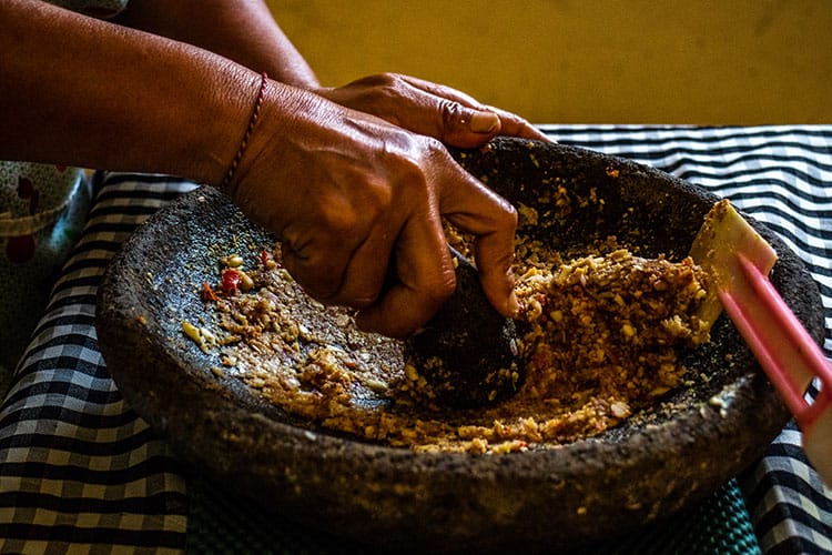 Grinding peanut sauce ingredients in an ulekan, or wide Balinese mortar and pestle. 