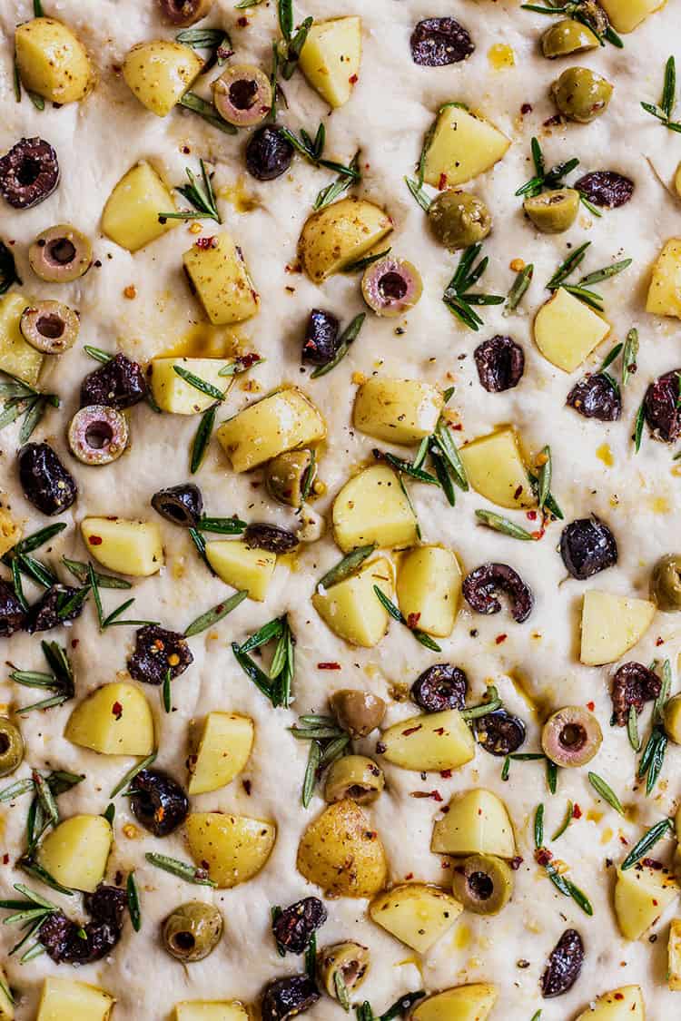 Potato foccacia topped with potato, olives and rosemary, ready to go in the oven. 