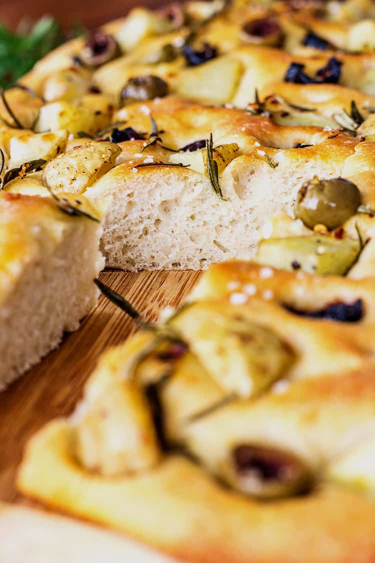Potato foccacia topped with olives, rosemary and potato, sliced and ready to serve. 