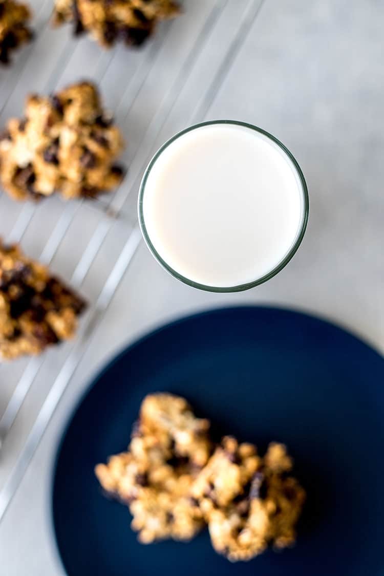 Gluten-free vegan cookies on a baking rack, alongside a glass of almond milk. 