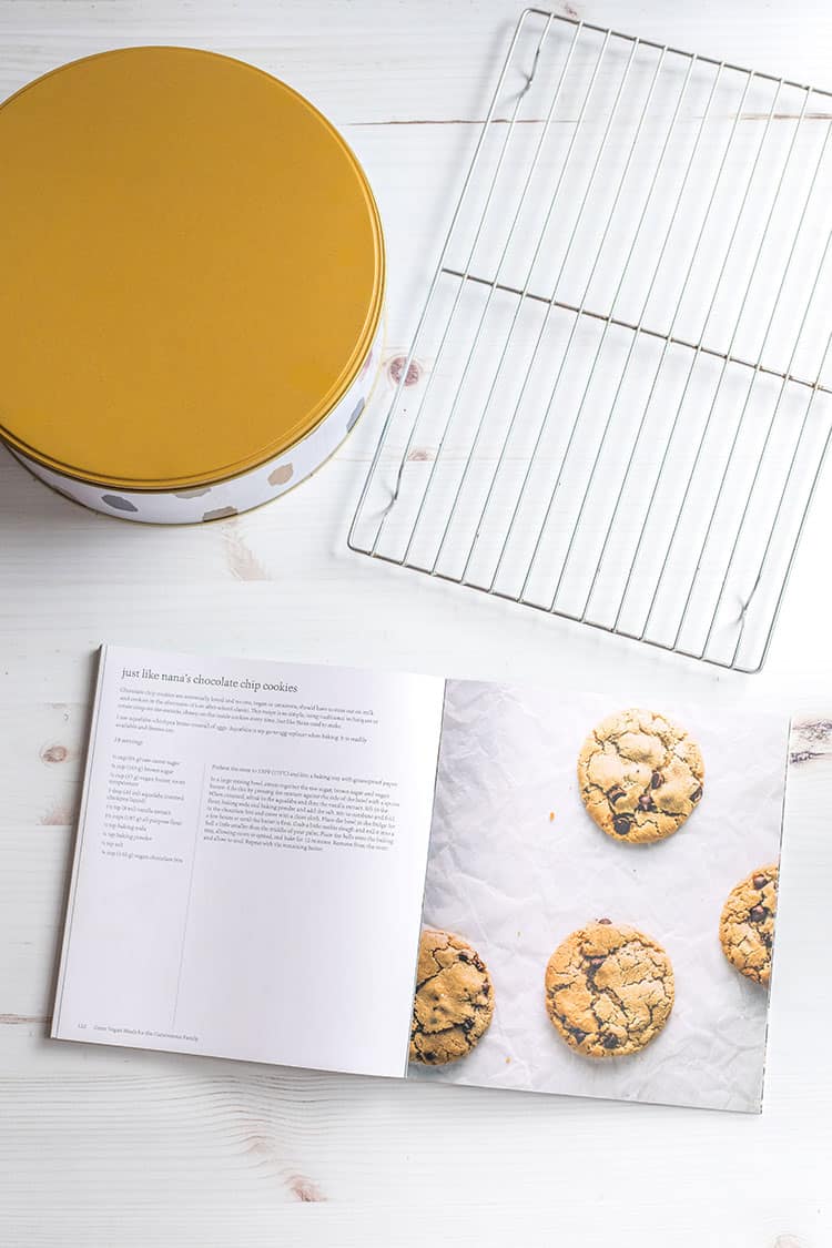 Picture of an open cookbook, cookie tin and cooling rack. 