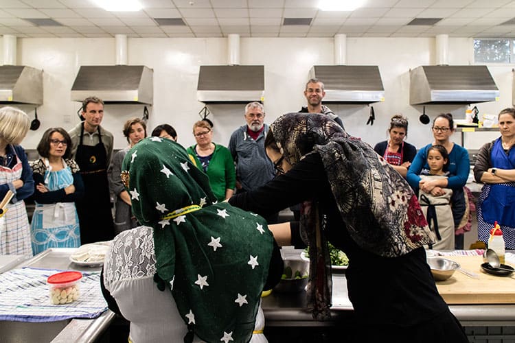 A group of cooking class attendees watching the Home Kitchen team demonstrate recipes. 