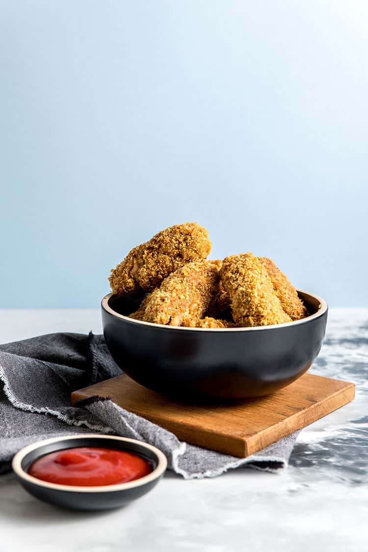 A bowl of jackfruit and chickpea vegan nuggets, with a small dish of ketchup alongside. 