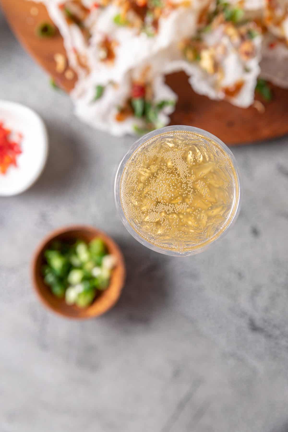 A glass of sparkling wine sitting next to a platter of Vietnamese rice paper crisps. 