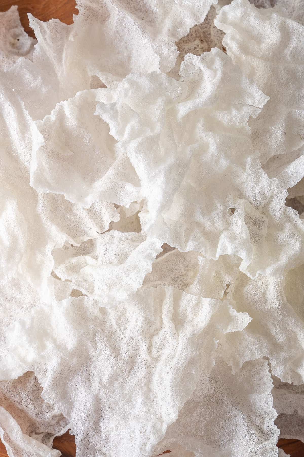 Fried rice paper crisps piled on a wooden serving board. 