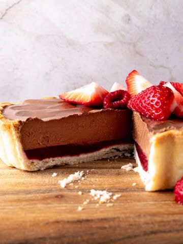 Side view of a sliced chocolate mousse tart, showing a layer of raspberry gel under the chocolate mousse.